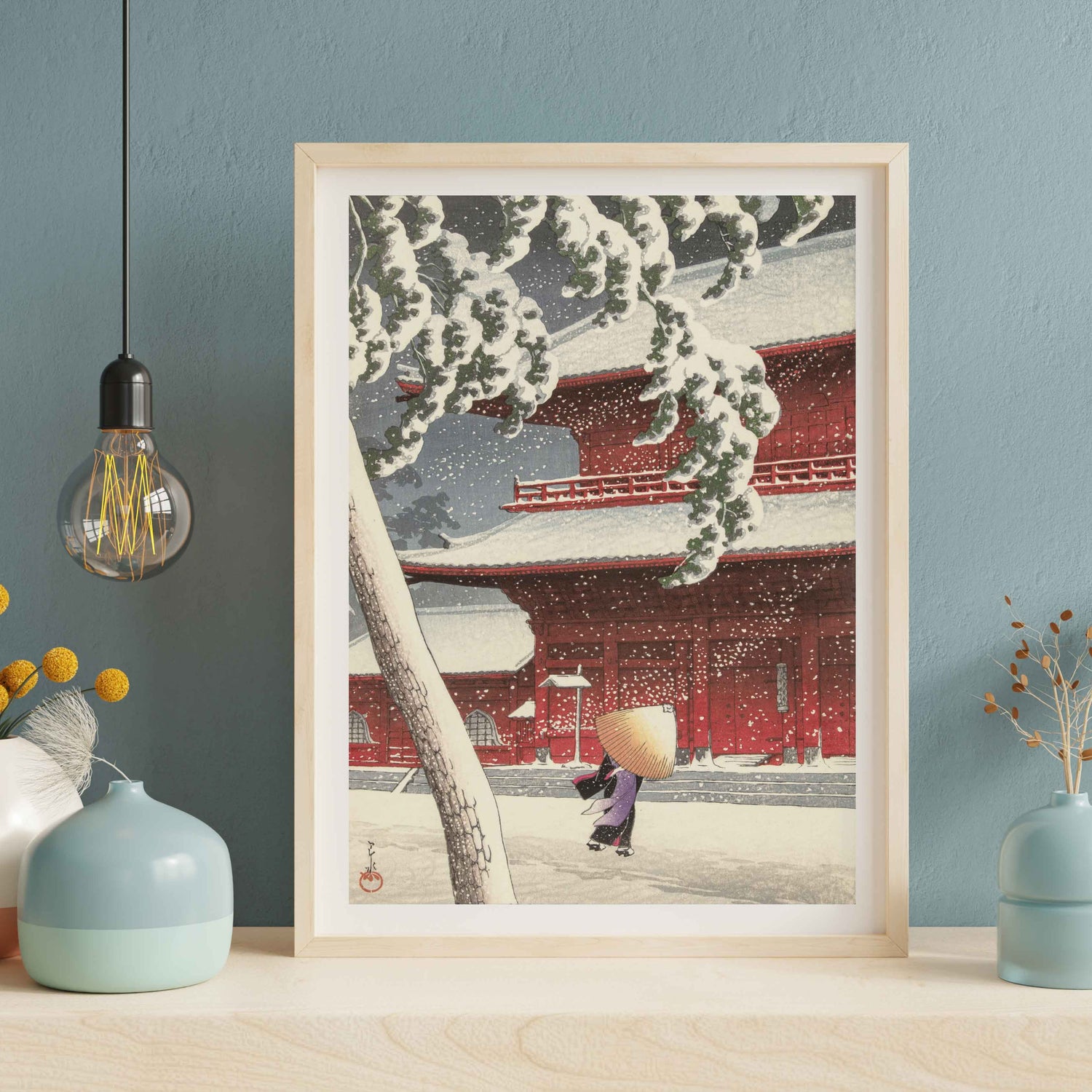 Kawase Hasui woodblock print of a figure in snow near a red temple, wearing a traditional straw hat