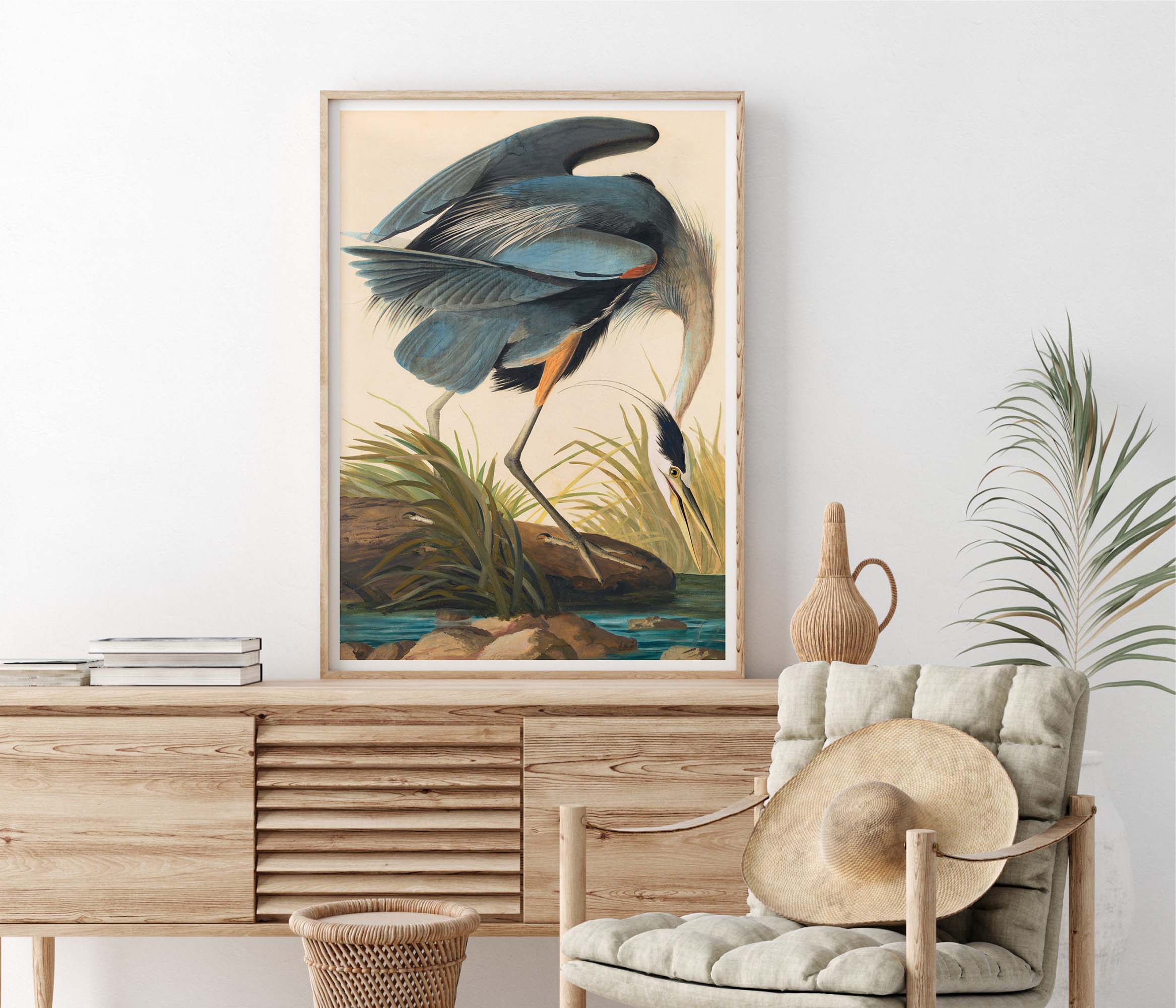 Framed artwork of a blue heron by John James Audubon  on a wall above a wooden console table with decorative items.