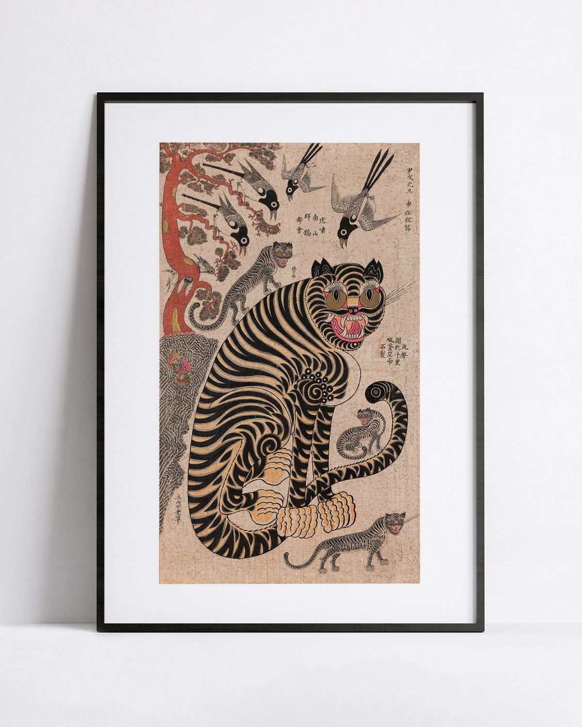 A framed art print featuring a traditional Korean-style illustration of a black and tan tiger with smaller tigrs and magpies  around it, displayed against a clean white wall.