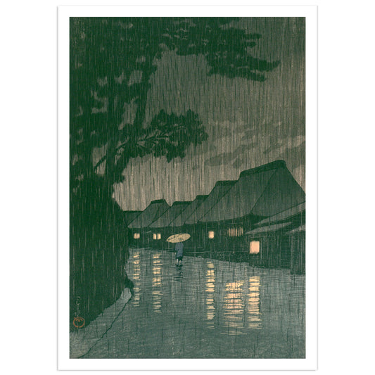 Sōshū Maekawa no Ame (Rain at Maekawa, Sagami Province) — Kawase Hasui. Japanese woodblock print depicting a solitary figure with a paper umbrella walking a flooded village road at night in heavy rain, lantern light reflecting on wet ground, deep green pine trees looming overhead. Shin-hanga art print.