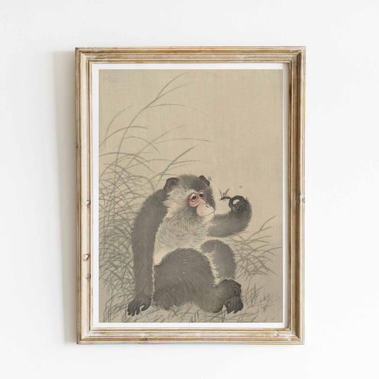 A seated monkey holds a dragonfly gently on its hand, gazing at it with gentle curiosity. Rendered in muted tones without black outline, the print emphasizes subtle feather and insect detail. Reproduction of the Japanese woodblock "Monkey Holding a Dragonfly" by Ohara Koson. Framed
